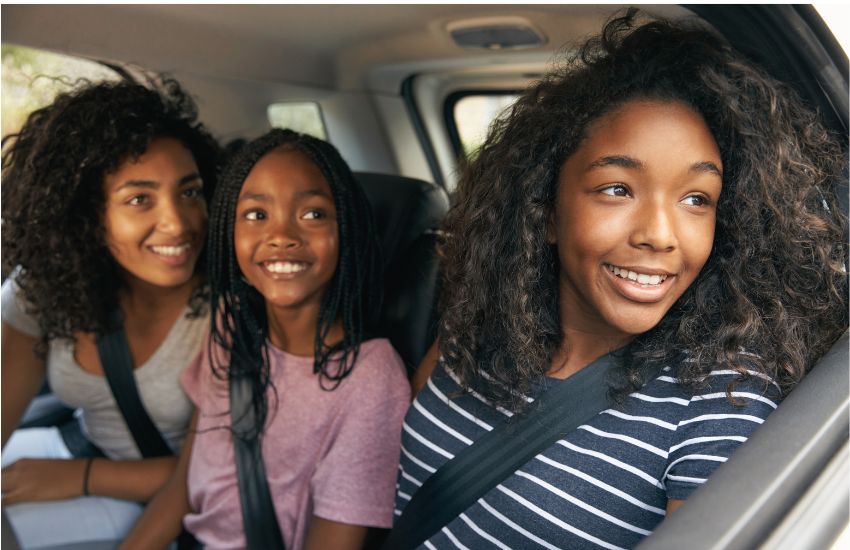 Family with teenage girls enjoying view from the car on road trip